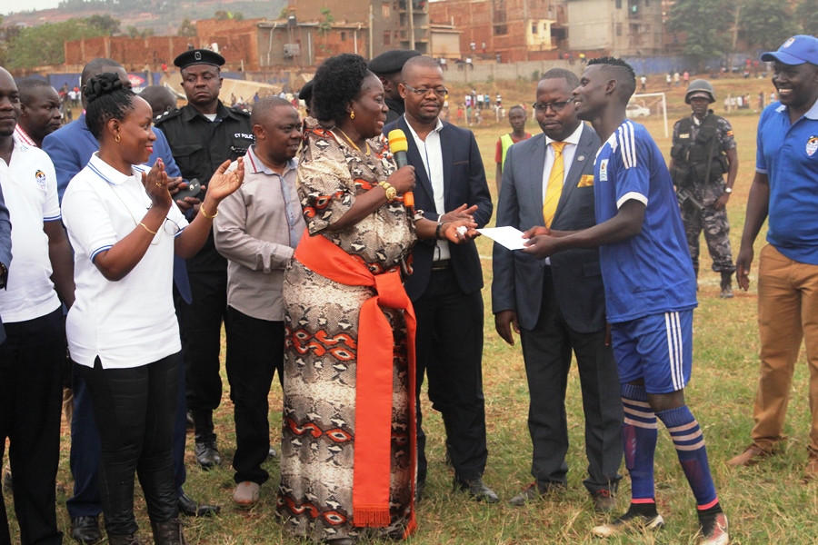 Speaker of Parliament Rt. Hon. Rebecca Kadaga hands over an envelope with cash to Busoga striker Joel Madondo after the match