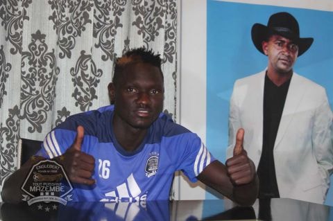 Joseph Ochaya posing in TP Mazembe jersey alongside the picture of club owner, Moise Katumbi Chapwe